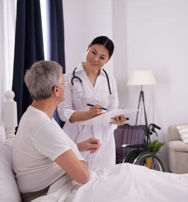 A healthcare provider discussing medication options with an elderly male patient in a home setting, focusing on prior authorization requirements for Temazepam with Caremark.