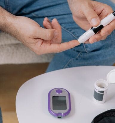 rson using a safety pen needle for diabetes management, showing the process of blood glucose testing.