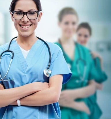 Smiling nurse in blue scrubs with a stethoscope, standing confidently in front of a team of healthcare professionals, symbolizing teamwork in LTC.