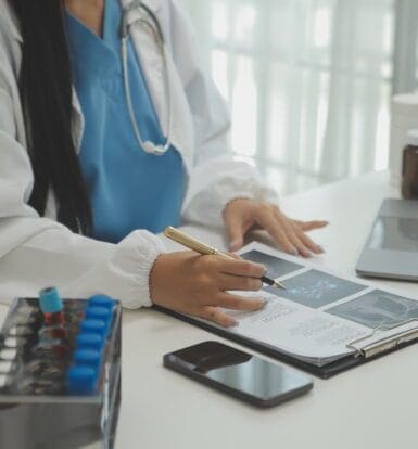 A medical scribe documenting a telemedicine consultation on a laptop.