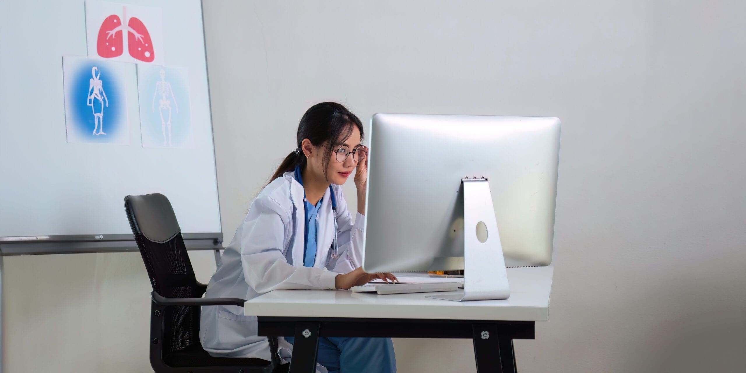 A healthcare provider interacting with a patient, while a medical scribe documents the visit in real time.