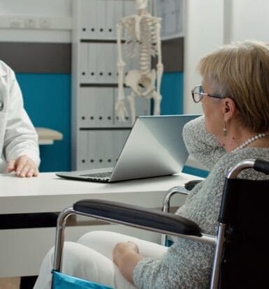 Doctor consulting a patient in a wheelchair about prior authorization for medication