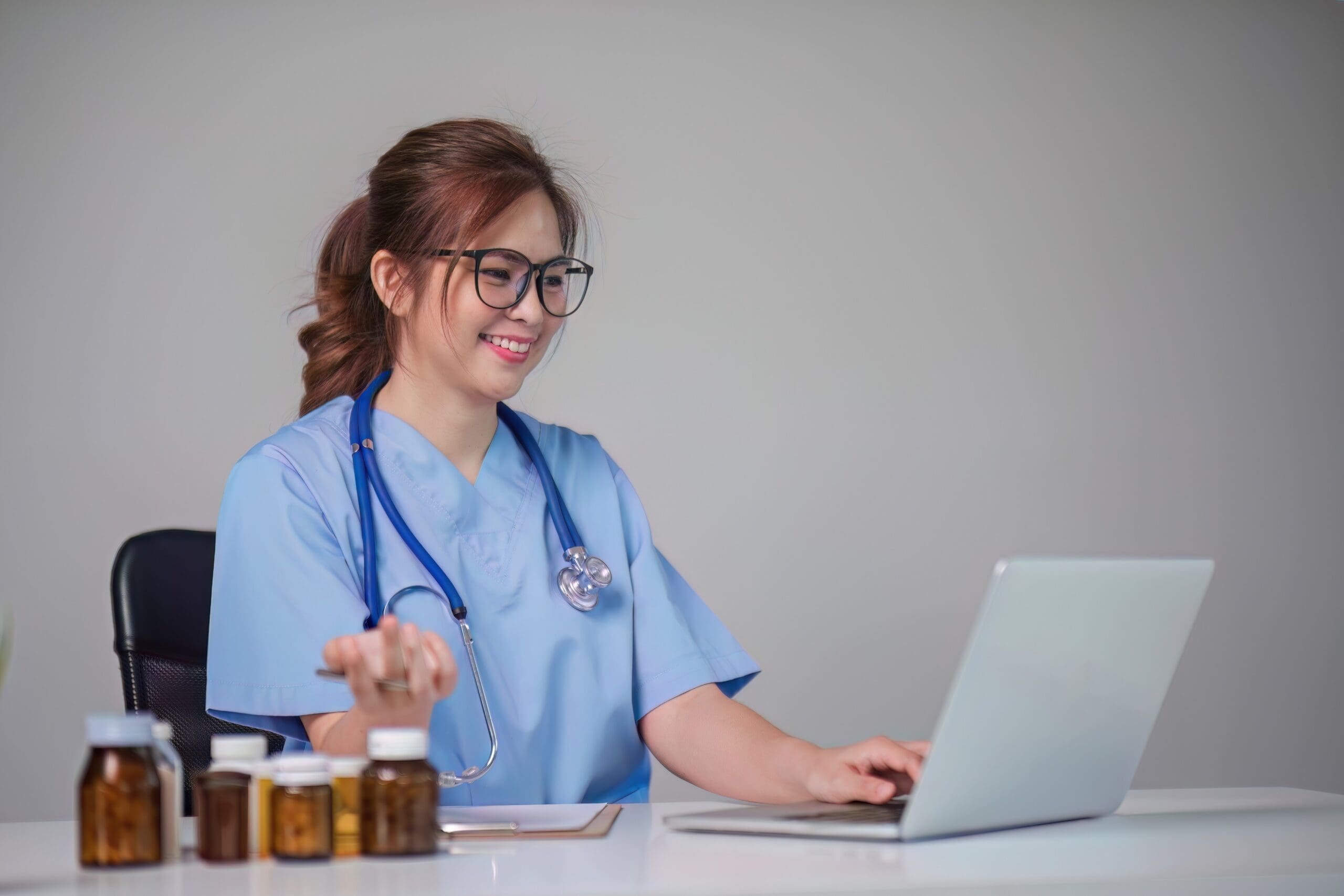 A female doctor in a white coat using a laptop while taking notes, with medical icons and digital health graphics in the background, representing the use of eClinicalWorks (eCW) for contact management.