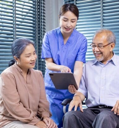 A nurse in blue scrubs showing a tablet to an elderly couple, symbolizing customized billing solutions for LTC facilities.