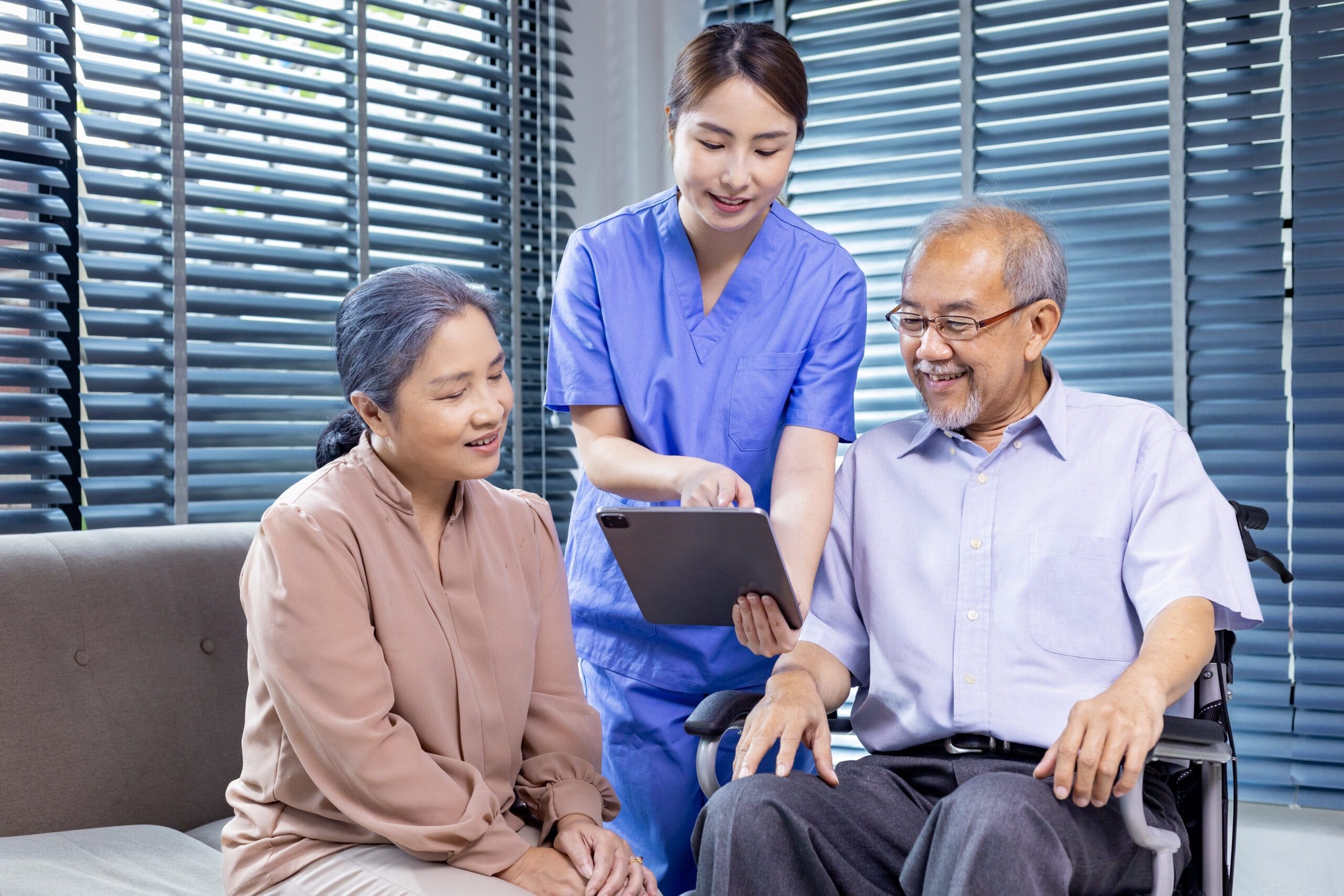 A nurse in blue scrubs showing a tablet to an elderly couple, symbolizing customized billing solutions for LTC facilities.