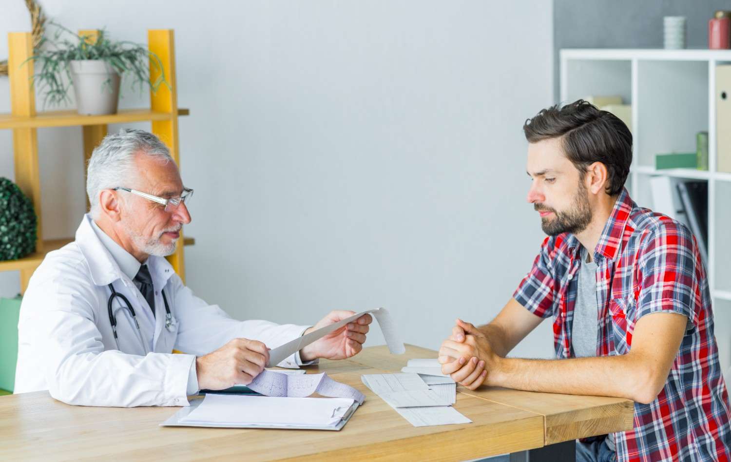 Doctor reviewing prior authorization paperwork with a patient in a clinical setting.