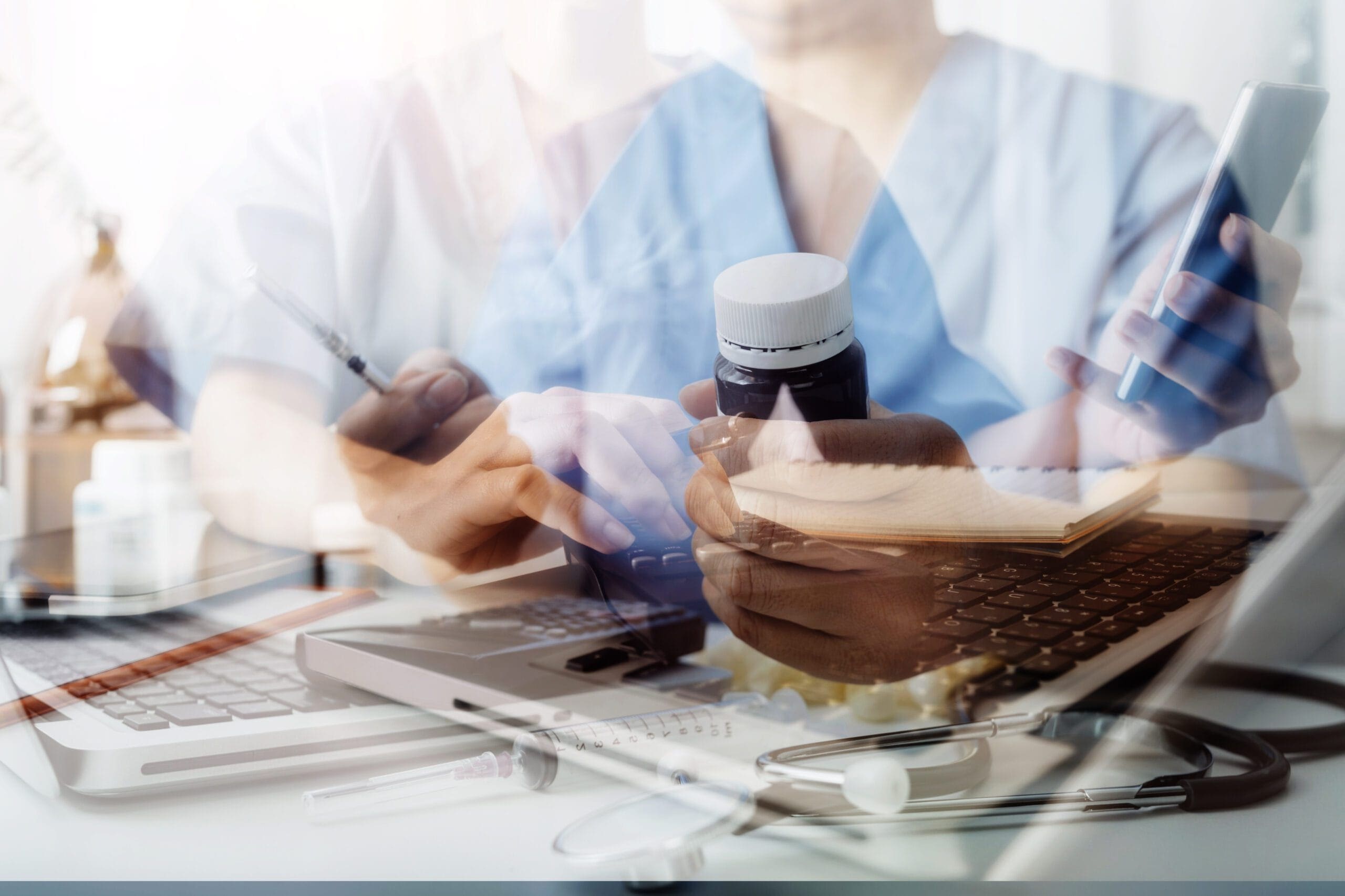 A physician consulting with a patient while a medical scribe documents the encounter on a computer.