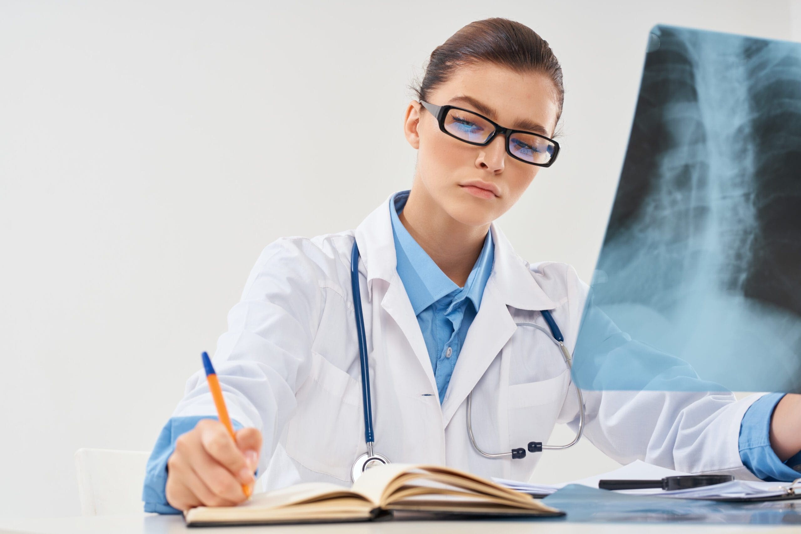 Medical coder working on a laptop, surrounded by healthcare documents and coding software.