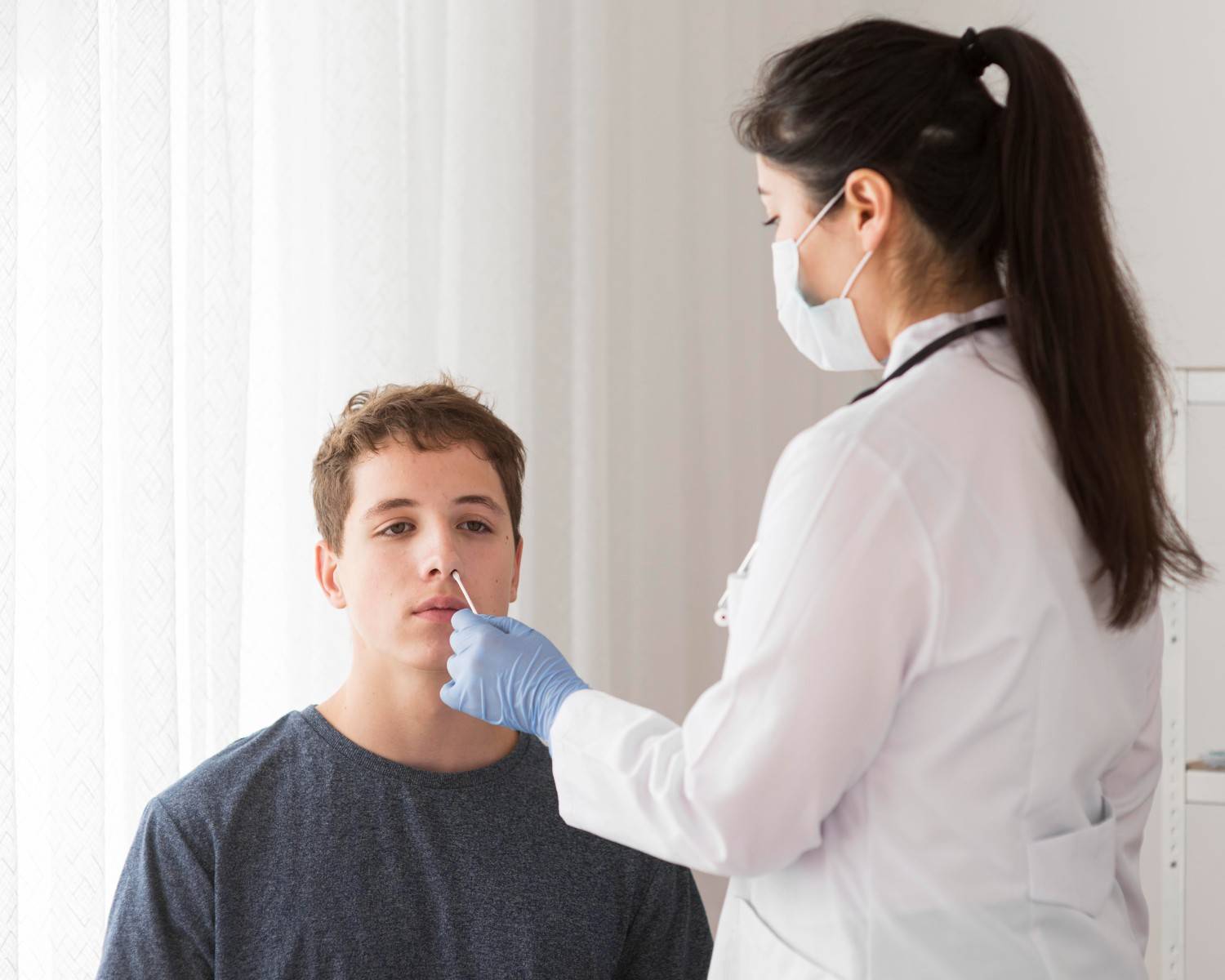 Doctor performing a nasal swab test on a young patient during a clinical visit, representing the careful documentation required in medical processes like prior authorization.