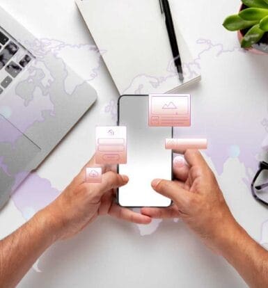 Hands using a mobile health (mHealth) app on a smartphone with digital interface icons, surrounded by a laptop, notebook, and coffee.