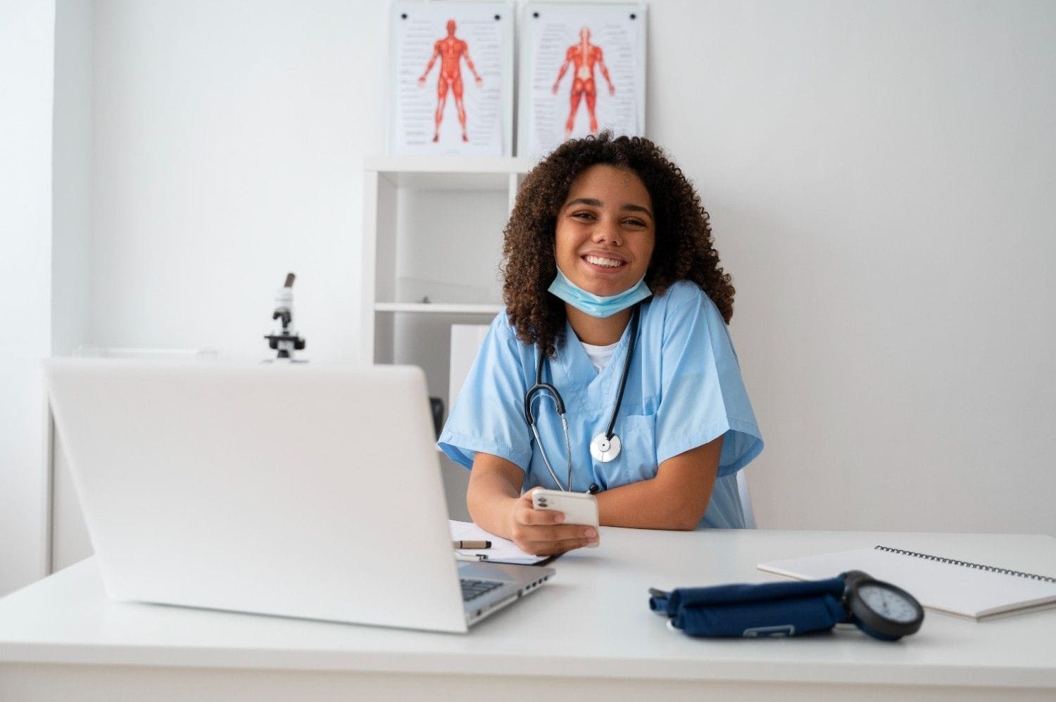 Smiling healthcare professional using a laptop and smartphone, showcasing the efficiency of Virtual Medical Assistants Healthcare services.