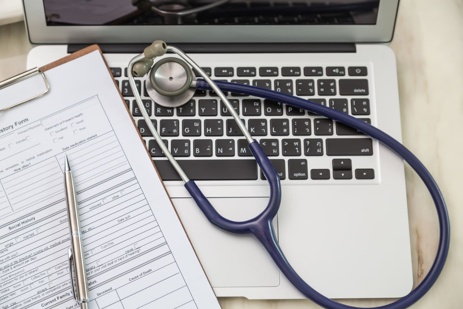 Medical history form and stethoscope on a laptop keyboard