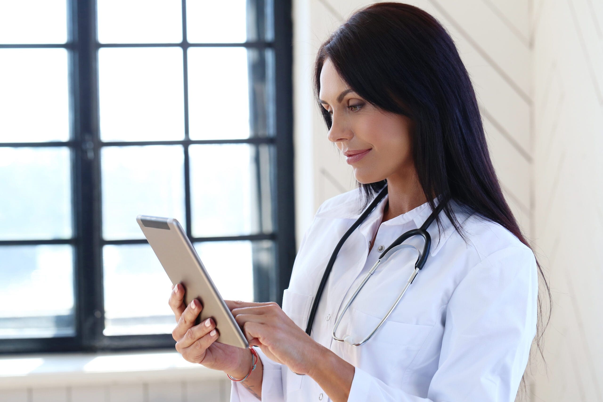 A determined female doctor meticulously reviews and enters medical data into a computer, ensuring accuracy and efficiency in patient care.