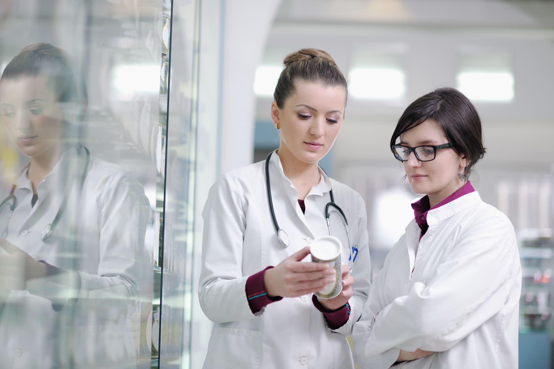 Two pharmacists reviewing a medication bottle in a pharmacy.