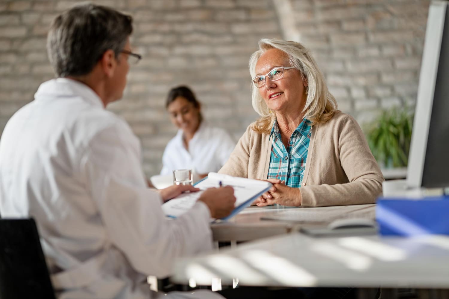 Healthcare professional consulting with elderly patient in clinic about outsourcing administrative tasks in Albuquerque