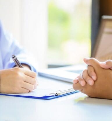 Doctor filling out paperwork during a patient consultation, highlighting administrative tasks in healthcare.
