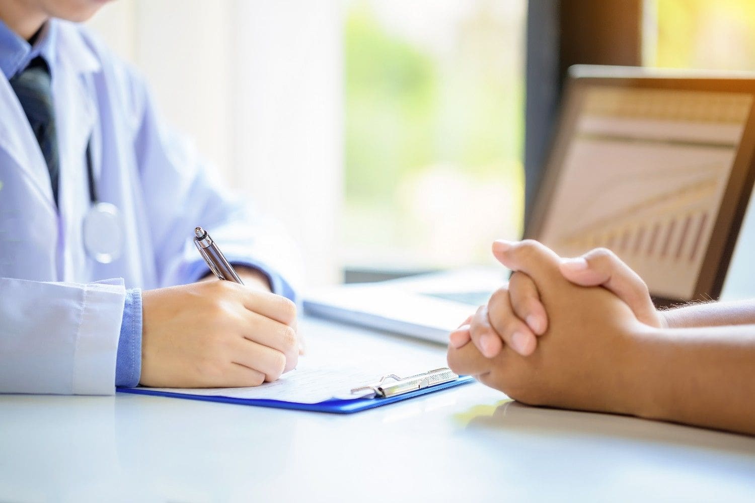Doctor filling out paperwork during a patient consultation, highlighting administrative tasks in healthcare.