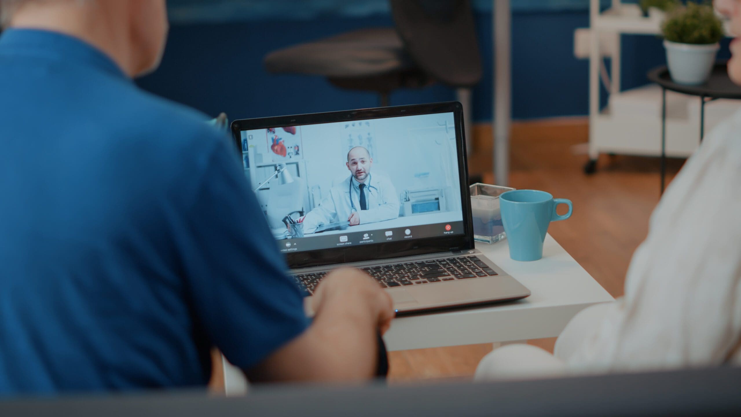 Virtual assistant for healthcare providers assisting a patient through a telemedicine consultation on a laptop screen.